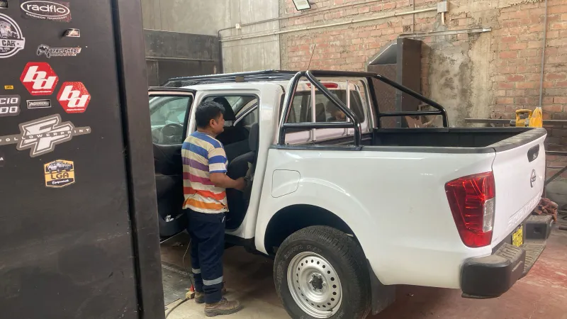 Pickup Nissan blanca con barra antivuelco en el taller